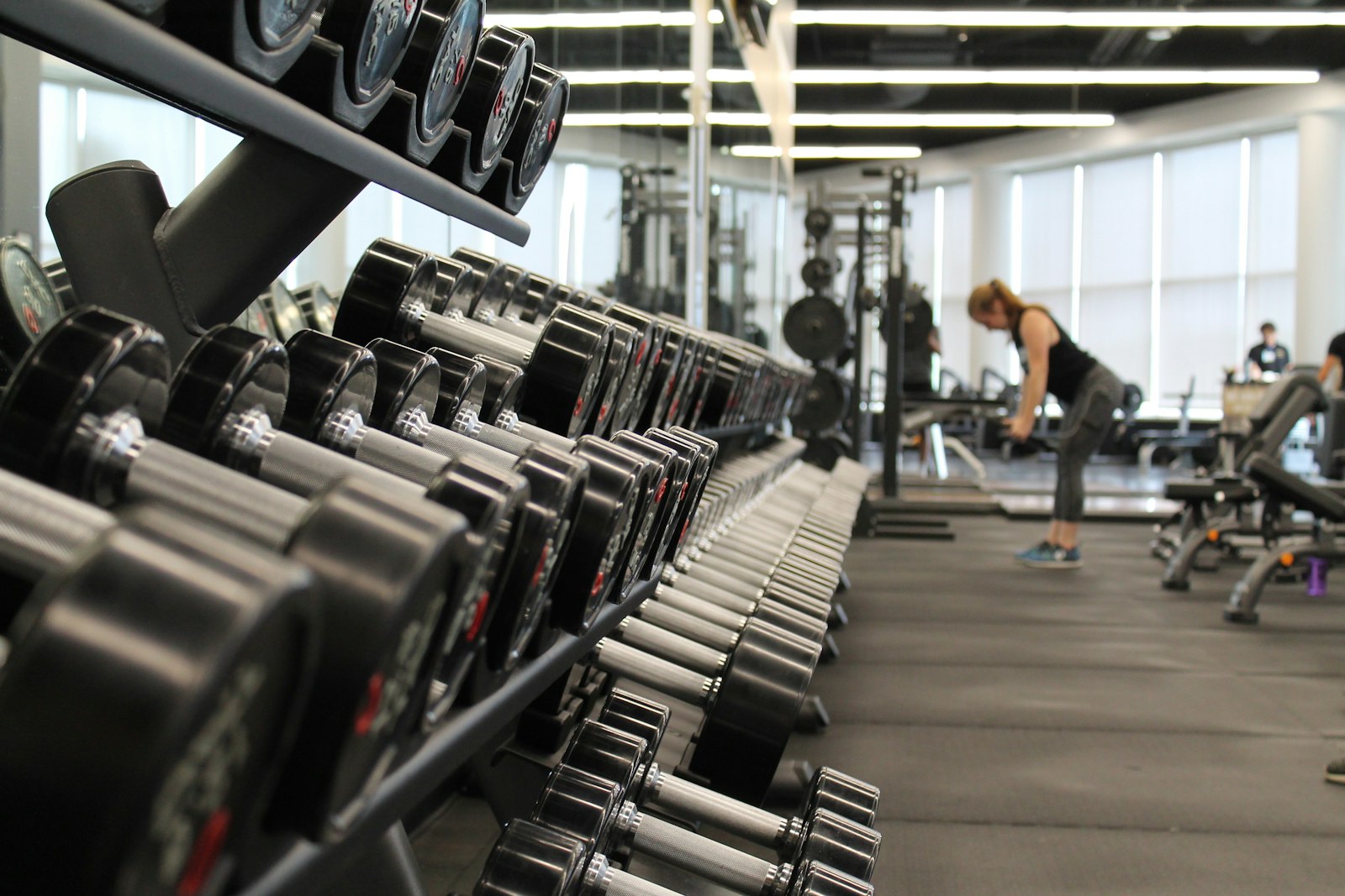 Pessoa olhando treino no celular dentro de uma academia de musculação